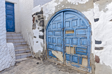 Blue door and a blue old ruined gate in a white painted house  - a typical Mediterranean Greek...
