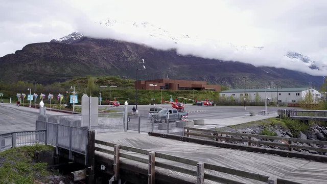 Tour red helicopters spooling up in a waterfront parking lot. ( Valdez Alaska)