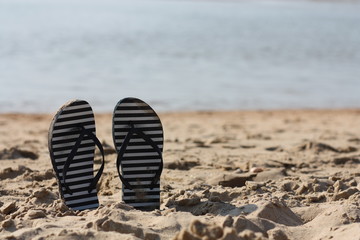 Naklejka premium Summer flip flops in the sand. Holiday feeling.