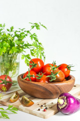Fresh tomatoes and parsley, dill, garlic on a light background in a rustic kitchen and wooden utensils still life with a copy space