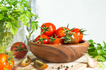 Fresh tomatoes and parsley, dill, garlic on a light background in a rustic kitchen and wooden utensils still life with a copy space