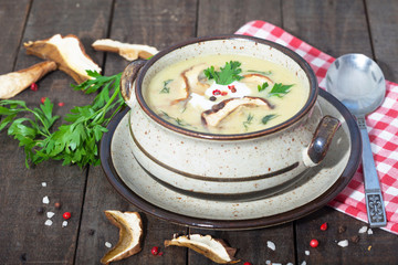 Mushroom cream soup with herbs and spices in a bowl on vintage wooden table.