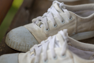 Old white sneakers of my daughter on a wooden floor