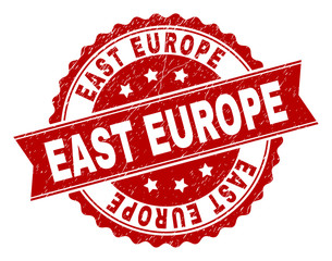 EAST EUROPE seal print with distress texture. Rubber seal imitation has round medallion shape and contains ribbon. Red vector rubber print of EAST EUROPE title with unclean texture.