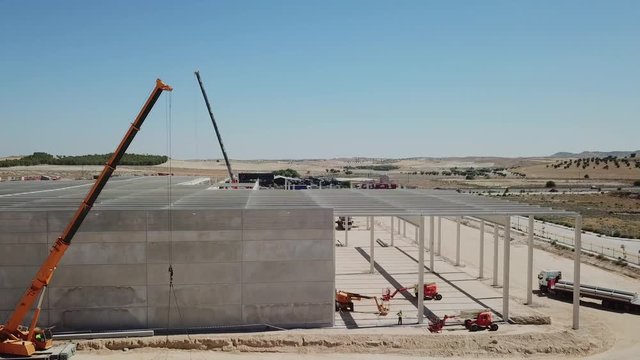 a&eacute;reo.colocaci&oacute;n de panel de hormig&oacute;n en el muro de una nave industrial en construcci&oacute;n .gr&uacute;a y operarios