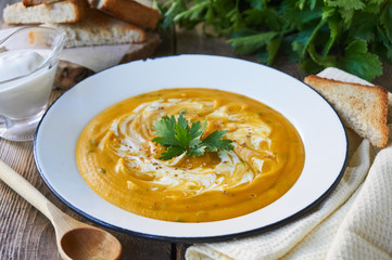 Carrot soup with sour cream and parsley in a bowl             