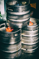 Used metallic beer barrels in the street in front of a pub. No people.