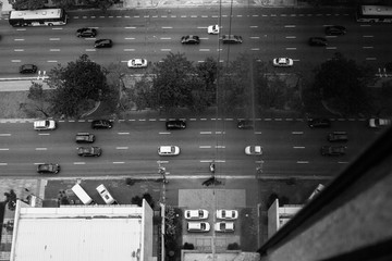 Black and white wallpaper background high view of the street with cars reflected on the glass walls of a business building.