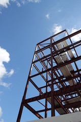 A framework of a new building being built with a blue sky surrounding it.