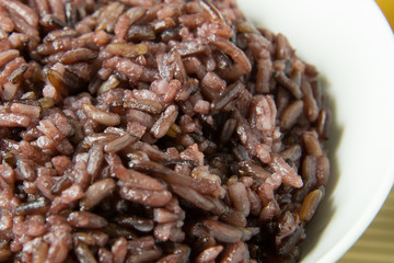 A Cooked rice berry ,Whole grain rice Thai black jasmine rice in bowl  on wood table.