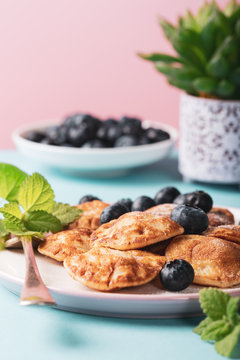 Dutch mini pancakes called poffertjes with blueberries, sprinkled with powdered sugar. Healthy food concept with copy space.
