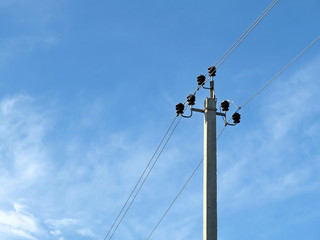Power pole on blue sky background with white clouds. Power transmission line with electrical wires and capacitors, electricity concept
