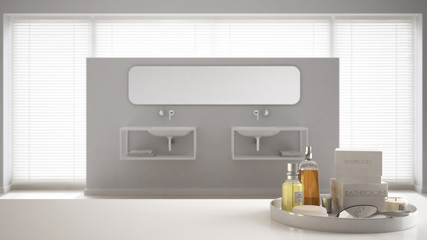 Spa, hotel bathroom concept. White table top or shelf with bathing accessories, toiletries, over blurred minimalist bathroom, modern architecture interior design