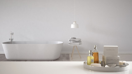 Spa, hotel bathroom concept. White table top or shelf with bathing accessories, toiletries, over blurred minimalist bathroom, modern architecture interior design