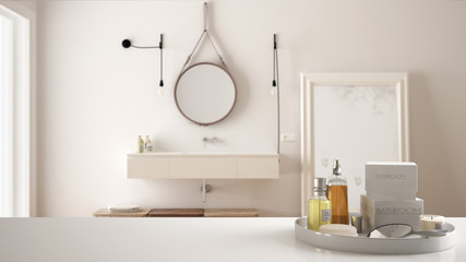 Spa, hotel bathroom concept. White table top or shelf with bathing accessories, toiletries, over blurred luxury bathroom, modern architecture interior design