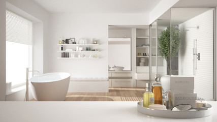Spa, hotel bathroom concept. White table top or shelf with bathing accessories, toiletries, over blurred minimalist bathroom, modern architecture interior design