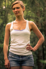 Young woman in a white tank top in the forest