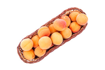 Several of harvested apricots in basket on white background..