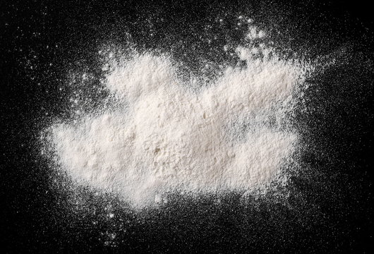 Pile of wheat flour isolated on black background, powder texture, top view with clipping path