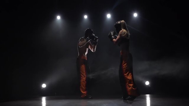 Guy they are sparring for kickboxing from the blow he falls to the floor. Smoke background. Slow motion. Light from behind