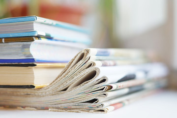 Pile of folded newspapers and books. Literature and tabloid media - different sources of information. Stack of paper goods, side view  