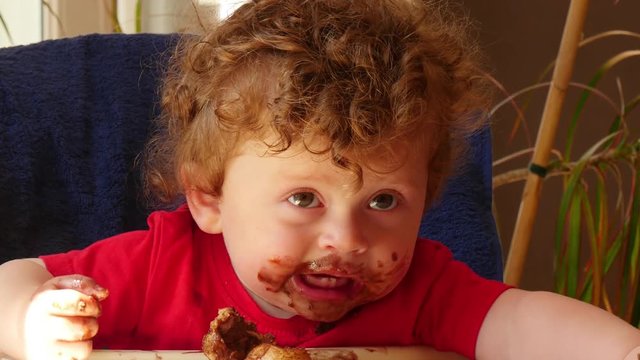 happy baby is eating a chocolate cake
