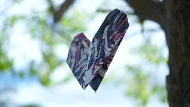 Paper heart hanging on tree, moved by the wind, bokeh background