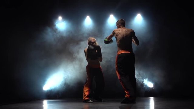 Men with a girl preparing for a kickboxing competition. Light from behind. Smoke background. Slow motion