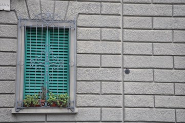 Fototapeta na wymiar Yellow window sills and green plants on a brick building wall