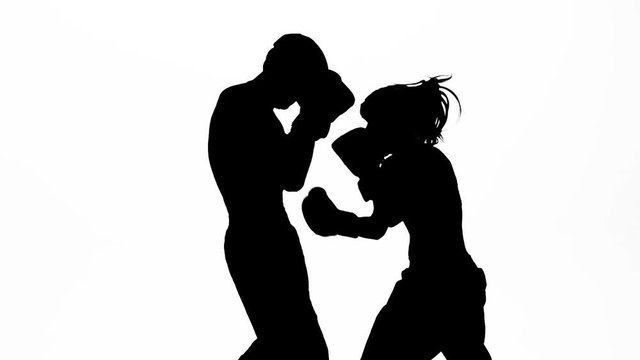 Guy with a woman boxing gloves beating in the ring . Silhouette. White background. Slow motion