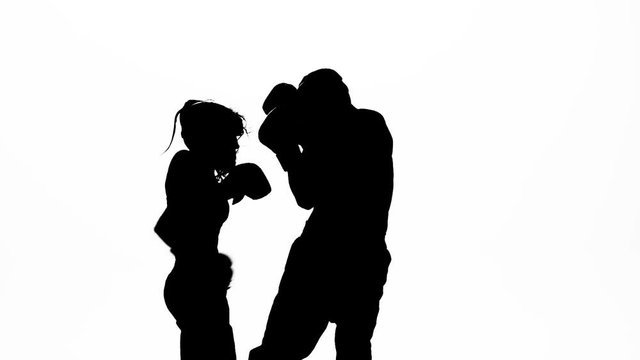 Men with a girl kickboxing gloves beating in the ring . Silhouette. White background. Slow motion