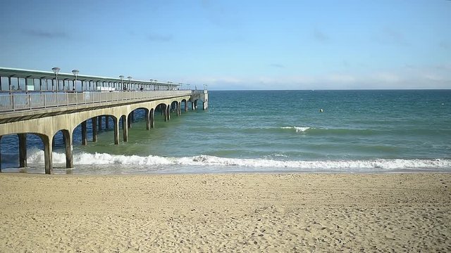 Boscombe pier during a beautiful day of summer. Waves moving towards shore in slow motion.