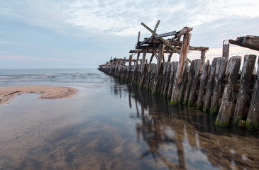 Fototapeta na wymiar An old wooden pier. Early morning at sea shore.