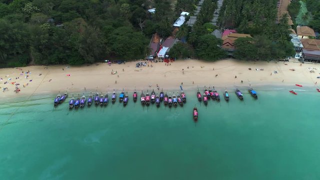 Little taxi boats laying at the beach of sunset beach in krabi reagion ao nang thailand. colorful excotic paradise nature with palms and turquoise ocean water - cinematic aerial drone shot