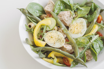Nicoise salad with tuna, eggs, green beans, yellow bell pepper, red cherry tomato, arugula, cucumber, spinach leaves and olives. Healthy diet concept
