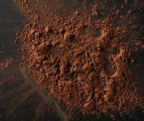 Cocoa powder pile isolated on black background, top view