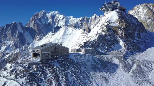 Aerial mountain ropeway and lodge from above with snow glacier drone shot