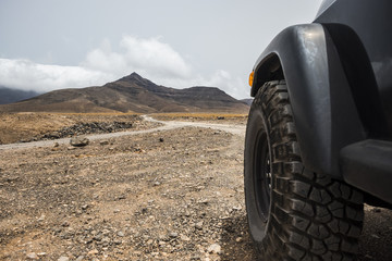 Fototapeta na wymiar big off road wheel from black high strong car explore the desert and the mountains in the country side. alternative way of travel and lifestyle for traveler in wanderlust