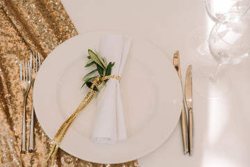 The white napkin decorated with gold thread and a branch of an eucalyptus
