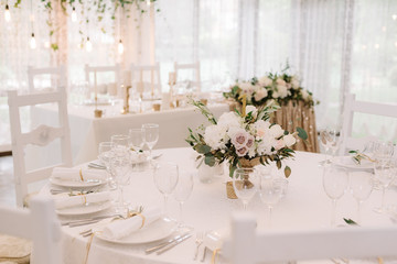 Round white table with graceful compositions of fresh flowers.