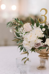 Decoration of a banquet table at a wedding with flowers in a gold vase.