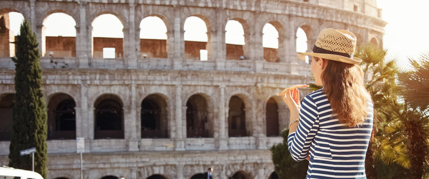 tourist woman in front of Colosseum in Rome, Italy eating pizza
