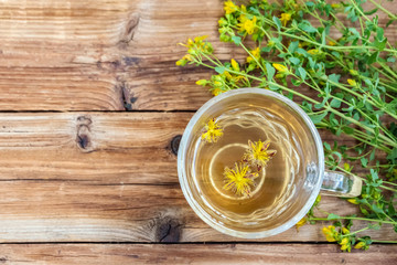 Cup of herbal tea from Hypericum - St. John's wort plant on wooden board table, top view. Copy space.