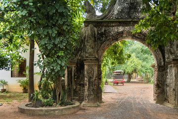 arch of stone in a buddhist temple with elegant tuk tuk in cambodia