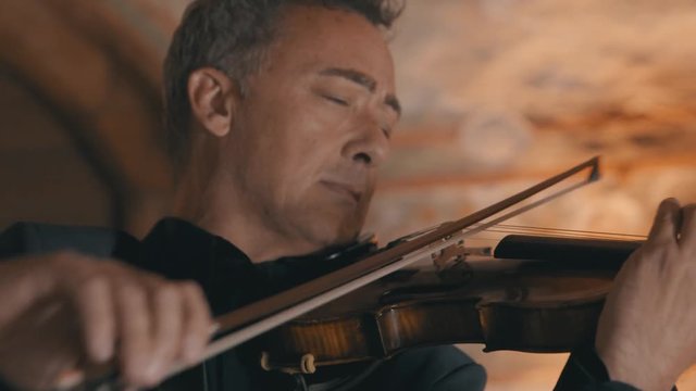 Close up shot of an older male violinist playing his violin with passion