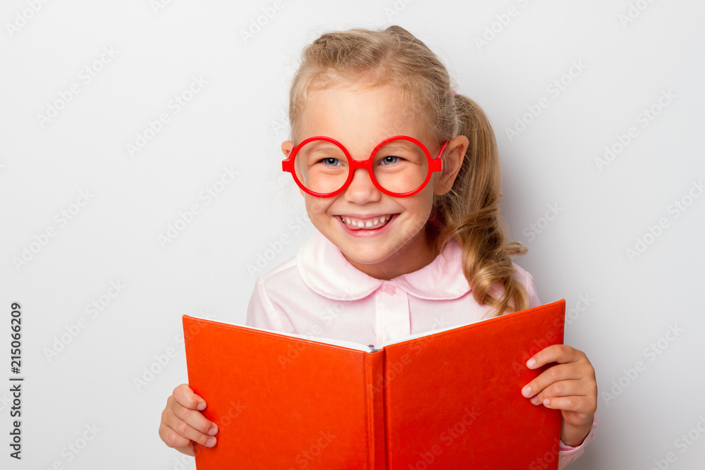 Wall mural little girl preschooler with glasses holds an open book