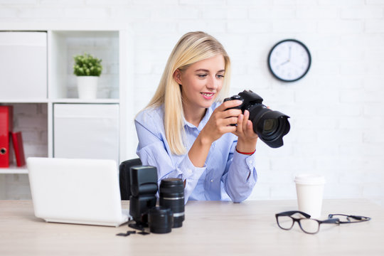 woman photographer sitting with computer and photography equipment and choosing best photos in modern office
