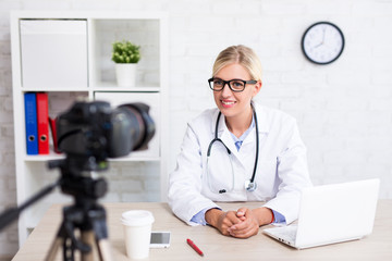 cheerful beautiful woman doctor recording vlog video about medicine