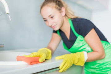 Closeup of female hands in rubber yellow gloves cleaning the cooker panel at home kitchen. Home, housekeeping concept. cleaning service