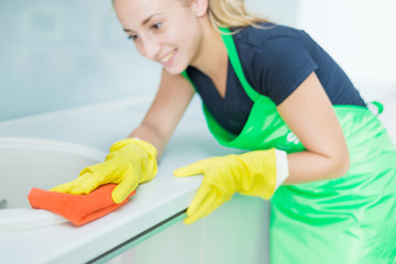 Closeup of female hands in rubber yellow gloves cleaning the cooker panel at home kitchen. Home, housekeeping concept. cleaning service